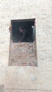 A Joyland window employee cutting the brick out of the wall to leave a wider opening so a larger window can be put in its place. 