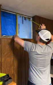 A Joyland Windows and Doors Employee meauring a window that needs to be replaced 